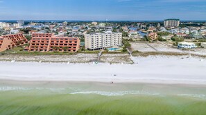 Un hotel costero con varias edificaciones, una playa y una vista despejada del océano.