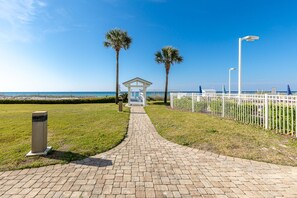 Ein gepflasterter Weg führt zu einem Pavillon mit Blick auf den Strand und den Ozean.