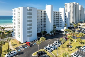 Ein mehrstöckiges Hotel mit Parkplatz und Blick auf den Strand.