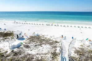 A beach with a clear view of the ocean, a sandy shore, and a few beach chairs and umbrellas. - Sterling Sands 604 2 Bedroom Condo (Destin)