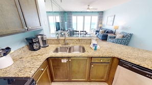 A kitchen with granite countertops, stainless steel sinks, and wooden cabinets. - Sterling Sands 604 2 Bedroom Condo (Destin)