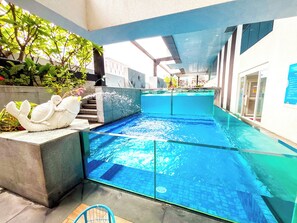 An indoor swimming pool with clear water, surrounded by walls with a blue and white color scheme, and a sculpture of a swan on a pedestal. - Grand Marina Residences (Paranaque)
