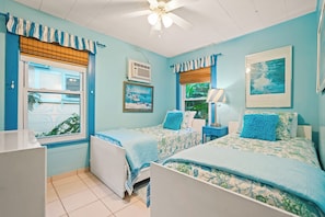 A bedroom with two beds, a ceiling fan, an air conditioning unit, and a window with a view of greenery. - Historic Shadow Point - Private Waterfront Estate & Gardens on 2.5 Acres! (Key Largo)