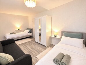 A hotel room with a bed, a sofa, a wardrobe, and bedside lamps.