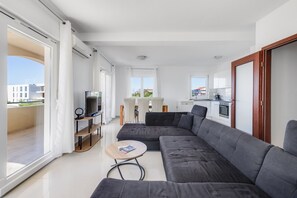 A modern living room with a sectional sofa, a TV, and a dining area with chairs. - Kotari Sukošan in Sukošan - Nord-Dalmatien / Kotari Sukošan in Sukošan - Appartement für 4 Personen AP5 (Sukošan)
