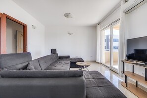 A modern living room with a sectional sofa, a small round table, and a flat-screen TV. - Kotari Sukošan in Sukošan - Nord-Dalmatien / Kotari Sukošan in Sukošan - Appartement für 4 Personen AP5 (Sukošan)