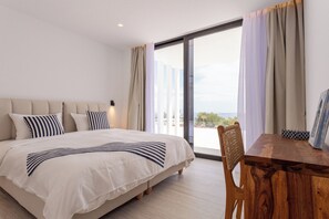 Ein modernes Hotelzimmer mit einem großen Bett, einem Esstisch und Blick ins Freie.