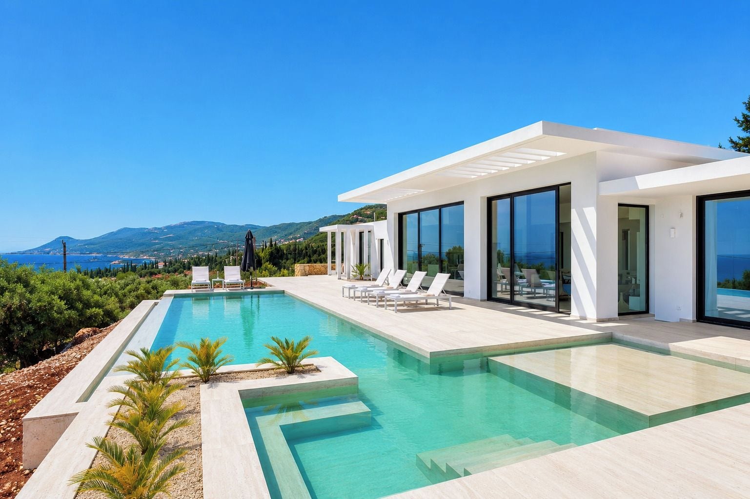 A modern pool area with clear blue water, surrounded by lounge chairs and a white building with large windows.