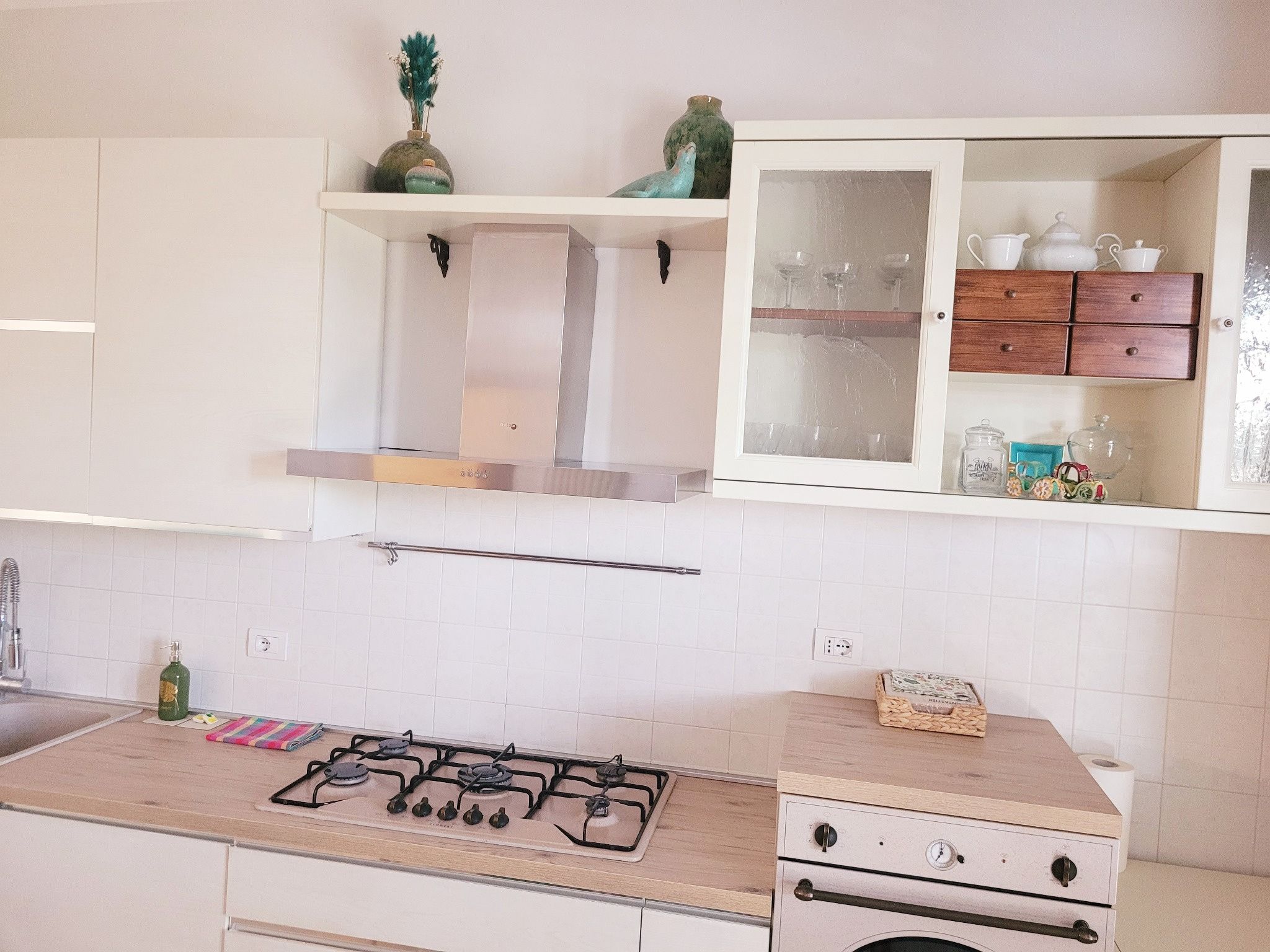 Eine Küche mit Gaskochfeld, weißen Schränken und einer Holzausziehtafel.