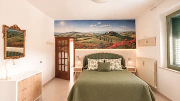 Una camera da letto con un letto, un comodino, una cassettiera, una porta e un affresco sulla parete.