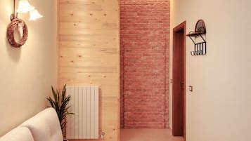 Ein Korridor mit Holzwand, Ziegelwand, weißem Heizkörper, einer Pflanze, einer Leuchte und einer Tür.
