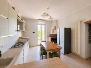 Una cucina moderna con zona pranzo, piano cottura a gas, frigorifero e finestra vista.