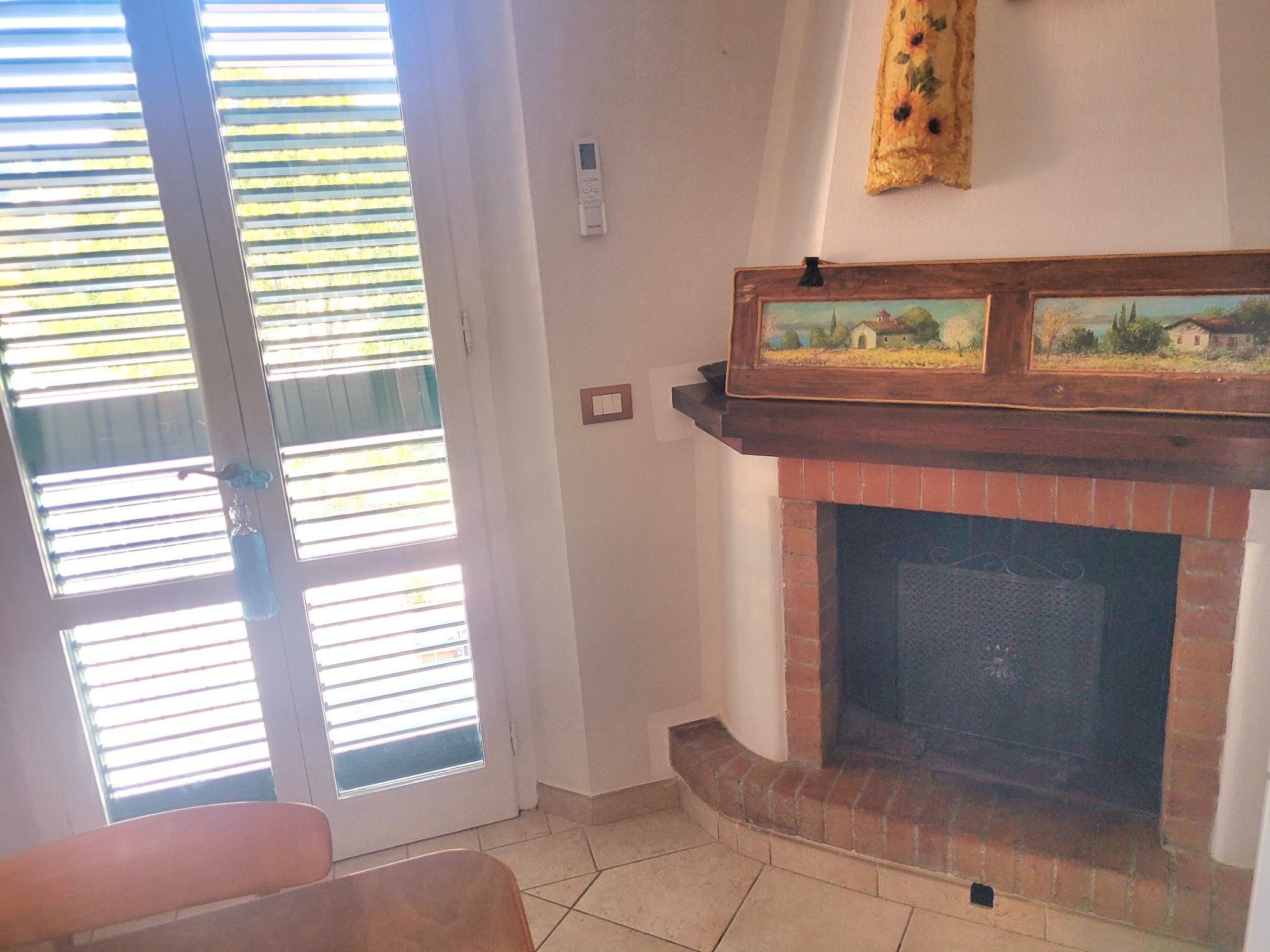 A room with a fireplace, a door with blinds, and a small table.