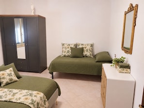 Una camera da letto con due letti, una cassettiera, uno specchio e un armadio.