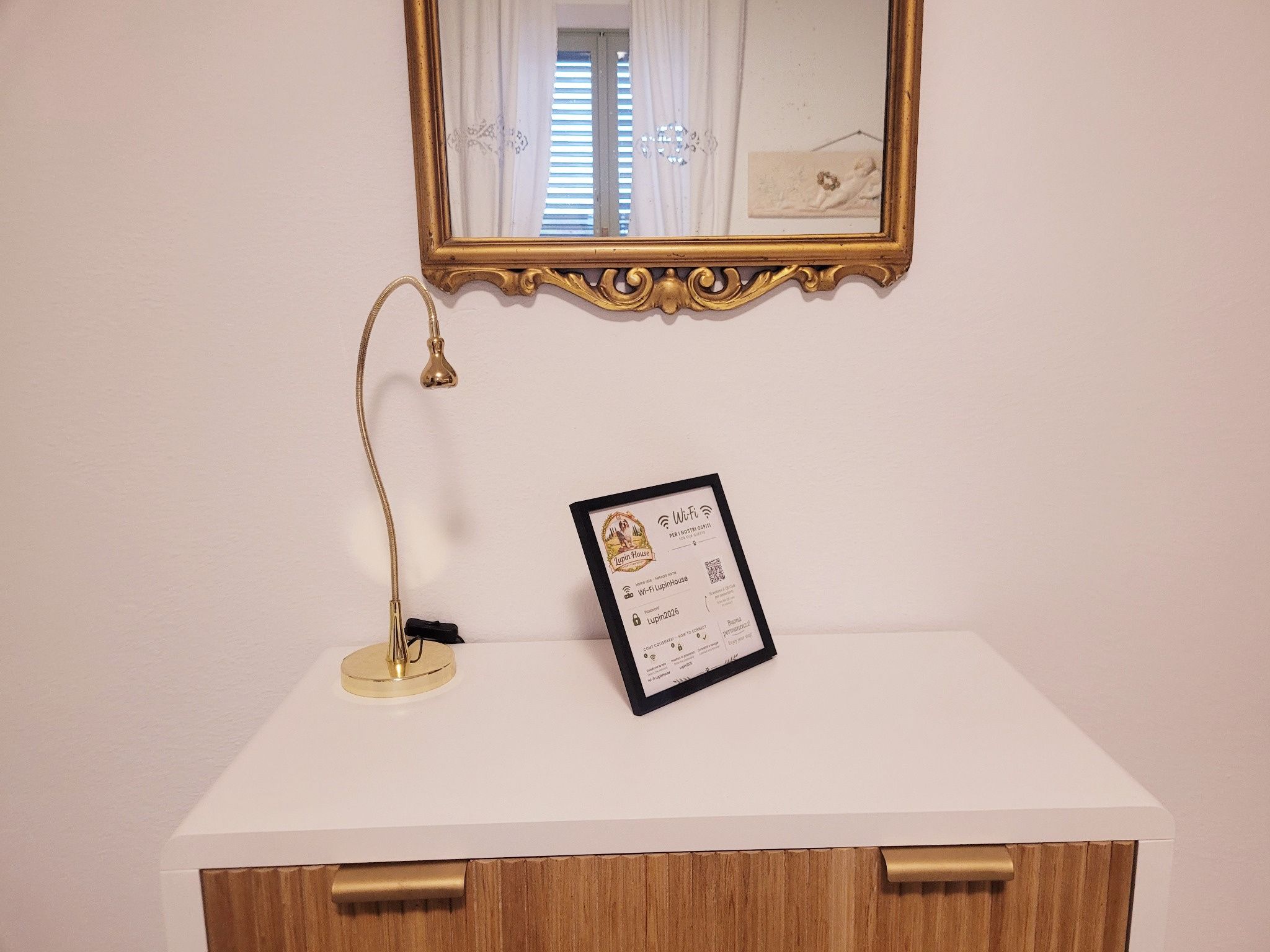 Een witte kaptafel met een gouden lamp en een lijst met het Wi-Fi-symbool.