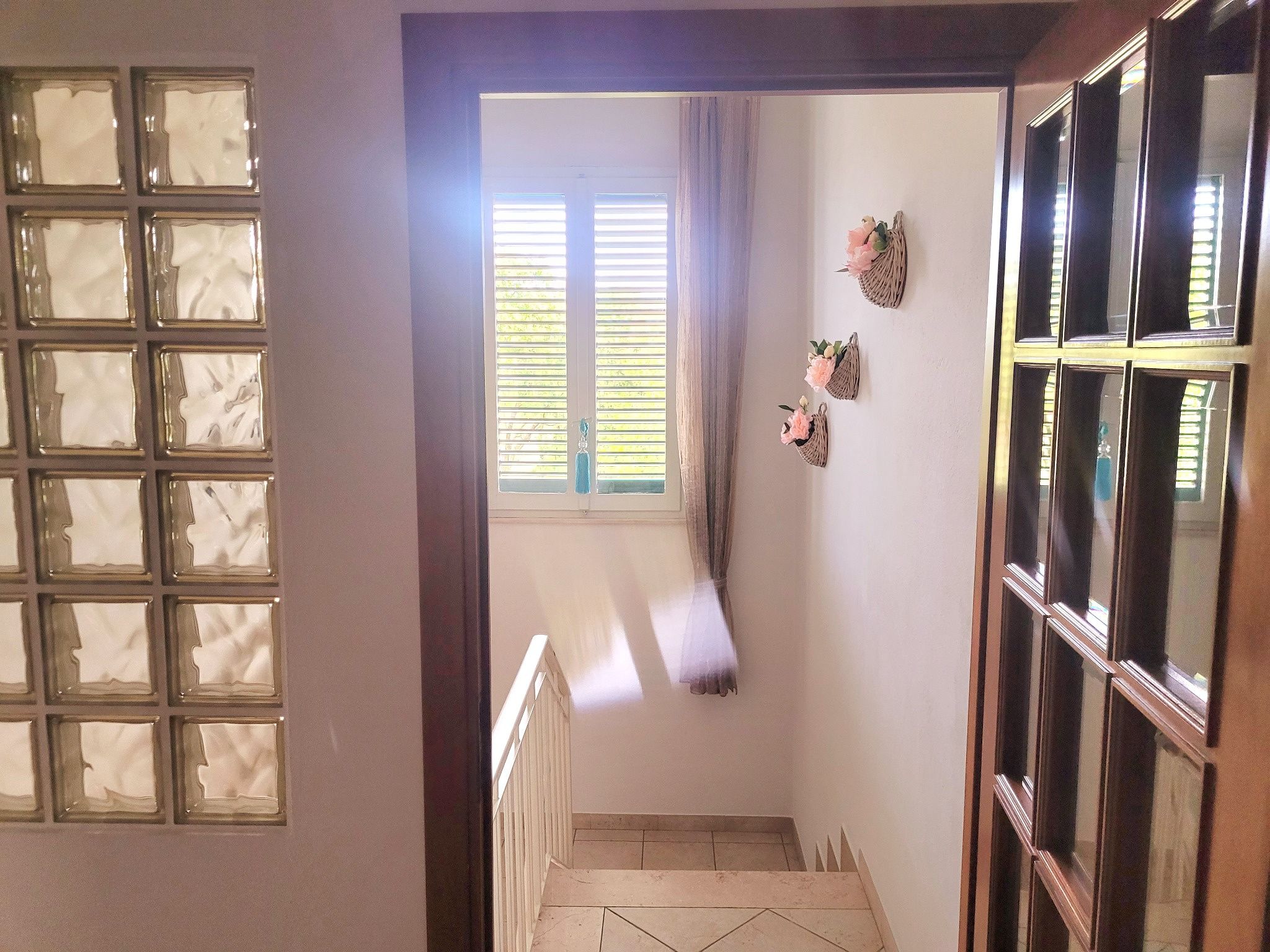Una escalera con vistas a una ventana y una puerta con paneles de vidrio esmerilado.