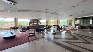 A spacious lobby with a bar area, seating arrangements, and a view of the outdoors.