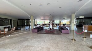 A spacious lobby with a central seating area, a reception desk, and a chandelier.