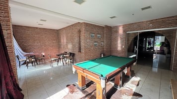 Una sala de billar amb un birilli, cadires i una paret de maó.