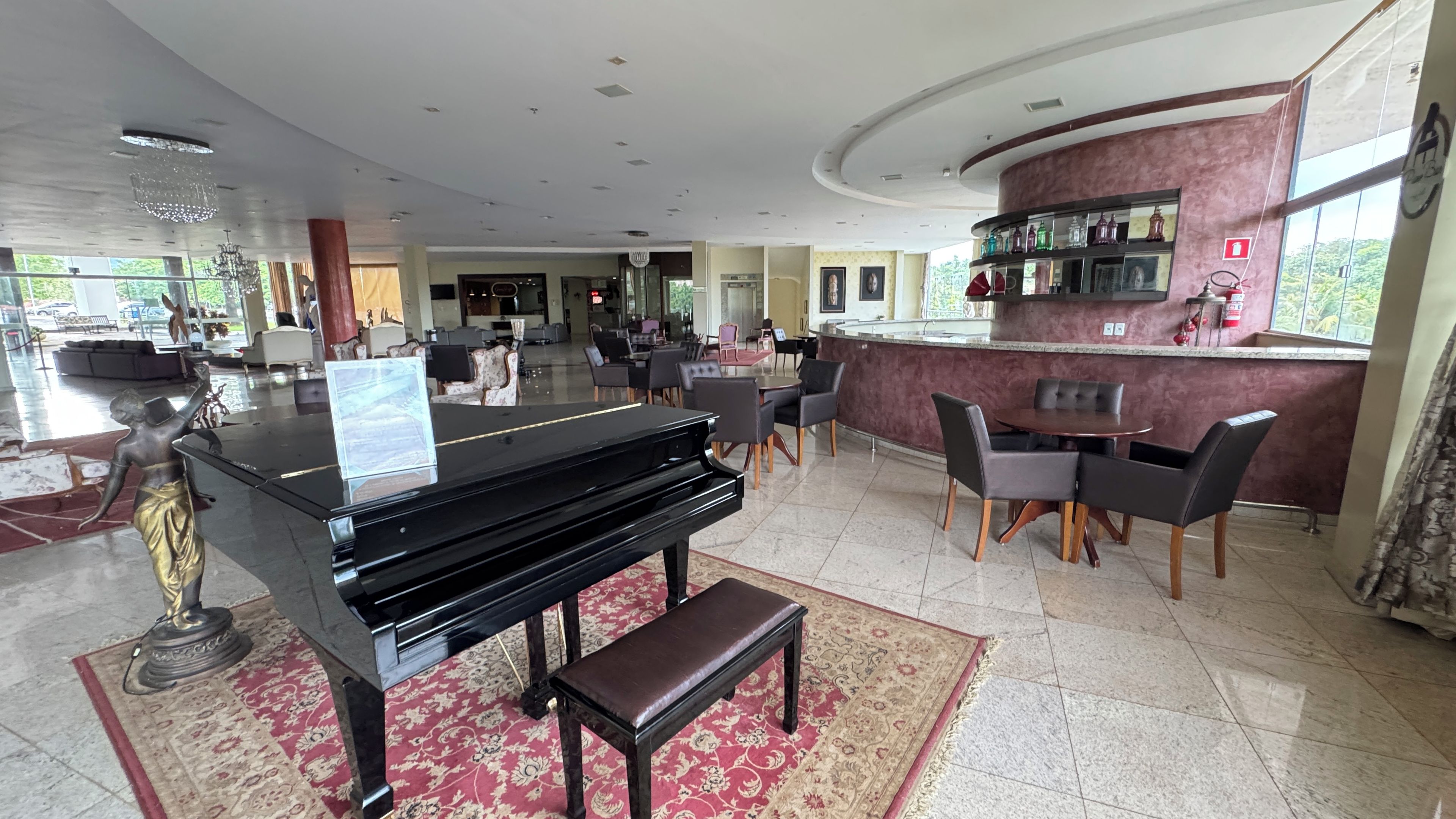 A hotel lobby with a grand piano, seating area, and a bar.