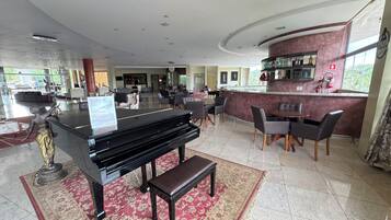 A hotel lobby with a grand piano, seating area, and a bar.