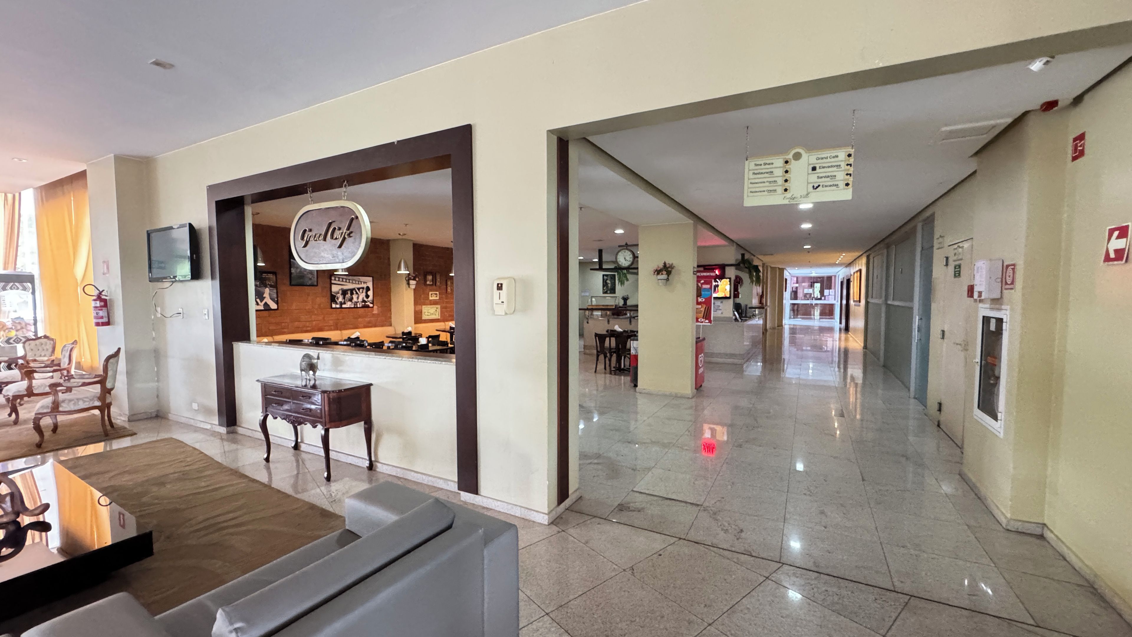 A hotel lobby with a reception desk, a seating area with chairs, and a clear view of the dining area.