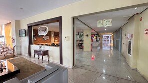 A hotel lobby with a reception desk, a seating area with chairs, and a clear view of the dining area.