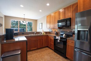 A kitchen with wooden cabinets, a stainless steel refrigerator, a microwave, an oven, and a sink. - Highland Greens Townhome: Long-Stay Lodging, Private Hot Tub (Breckenridge)