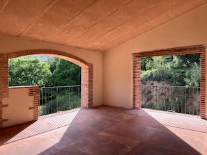A room with a tiled floor, brick arches, and a balcony with a metal railing. - Can Roig Farmhouse (Riells i Viabrea)
