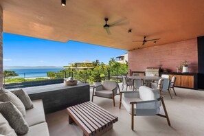 Ein moderner Außenbereich zum Sitzen mit Blick auf den Ozean, inklusive Deckenventilator und Bar.