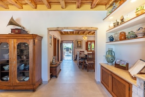 A hallway with a wooden cabinet, a dining area, and shelves with decorative items.
