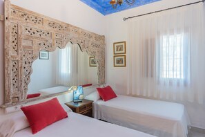 Ein Hotelzimmer mit zwei Betten, einem großen, verzierten Spiegel und einer Kandelaber.