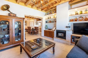 A spacious living area with a fireplace, wooden furniture, and a collection of decorative items on shelves.