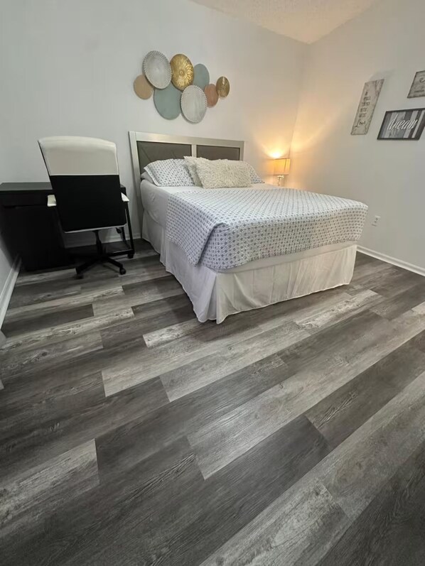 A bedroom with a bed, a desk, and a chair.