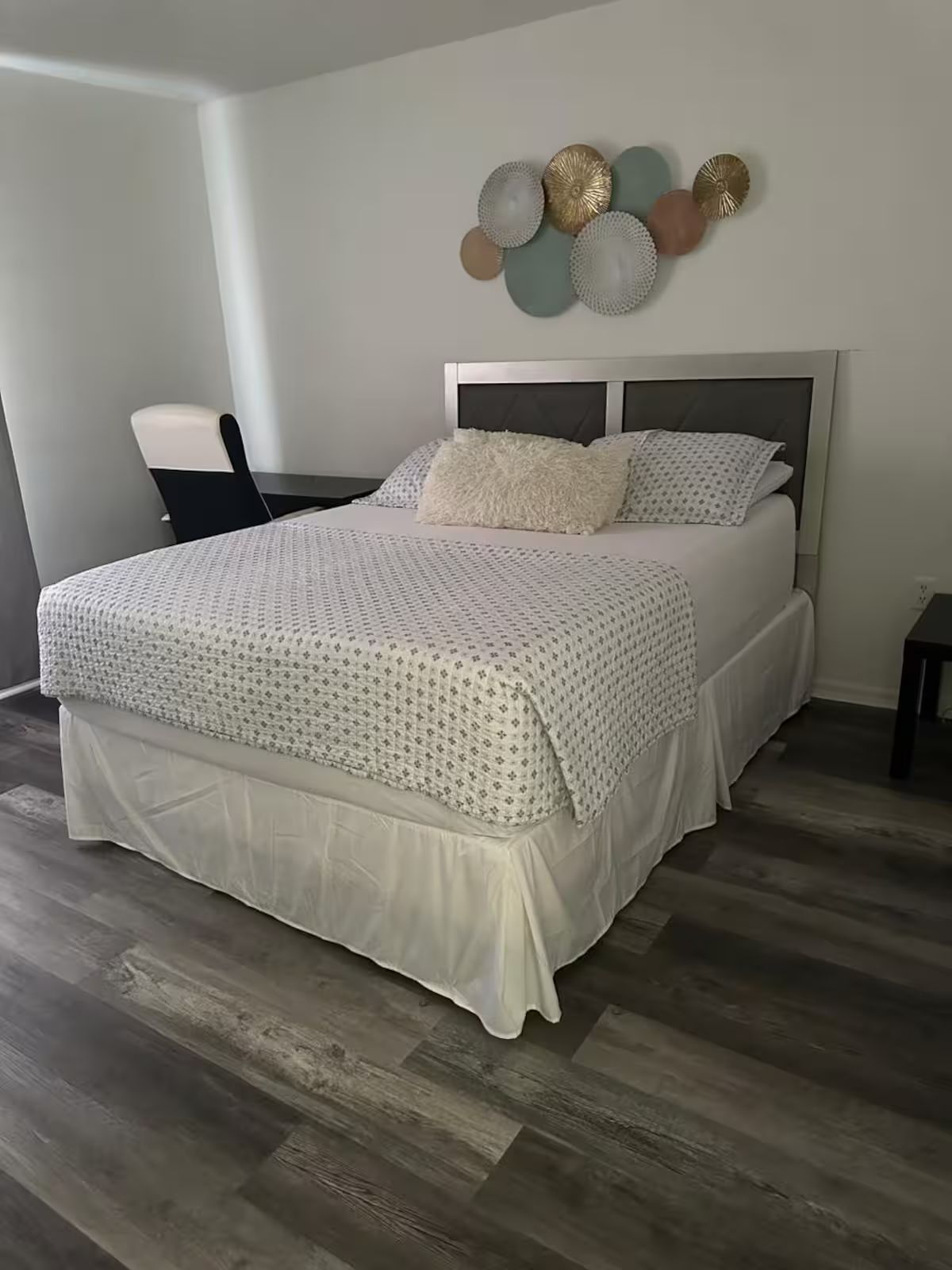 Une chambre à coucher avec un lit, une chaise et un élément décoratif mural.