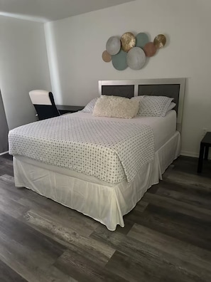 Un dormitorio con cama, una silla y un adorno en la pared.