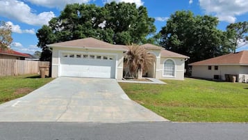 A residential property with a garage, a lawn, and a driveway leading to the house.