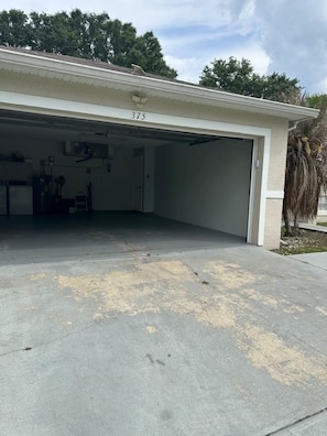 A garage with a number 375 on the door, a concrete driveway, and a palm tree in the background.
