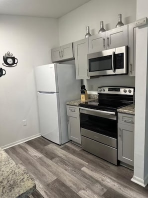 Una cocina equipada con refrigerador, microondas, estufa, horno y alacenas.
