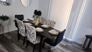 A dining area with a modern chandelier, round mirrors, and a large window with blinds.