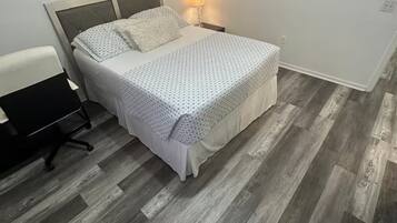 Ein Schlafzimmer mit einem Bett, einem Schreibtisch und einem Sessel. Es gibt Wanddekorationen und eine Lampe.