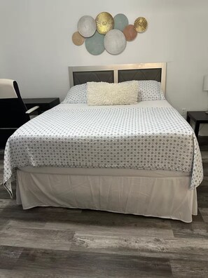 Un lit avec une couvre-lit à motifs, un oreiller moelleux et une jupe de lit assortie.