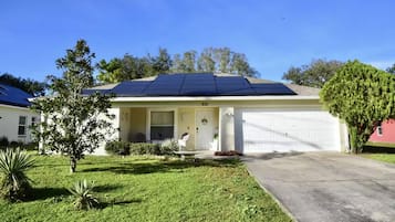 Une maison de plain-pied avec un garage, des panneaux solaires sur le toit et une pelouse bien entretenue.
