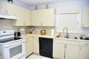 A kitchen with white cabinets, a stove, a dishwasher, and a sink.