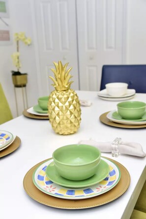 Een eettafel met een ananas als middelpunt, groene kommen en borden met gouden rand.