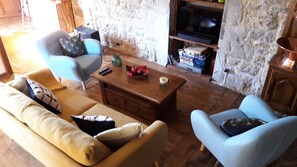 Ein Wohnzimmer mit einer Couch, Sesseln, einem Couchtisch und einem Fernseher.