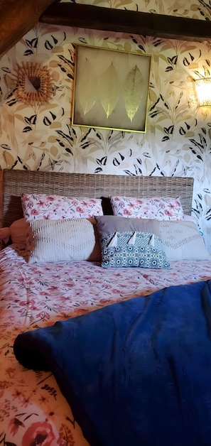 A bed with floral bedding, a woven headboard, and a wall with leaf patterns. - Gite 'Cap Del Mas' with Private Terrace and Wi-Fi (Ambeyrac)
