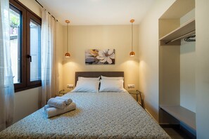 Ein Schlafzimmer mit einem Bett, zwei Nachttischen, einem Bild an der Wand und einem Fenster mit Vorhängen.