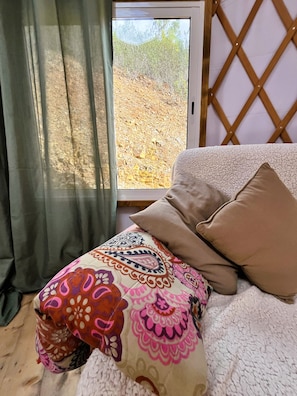 A room with a window, a bed with a patterned blanket, and a wooden lattice wall.