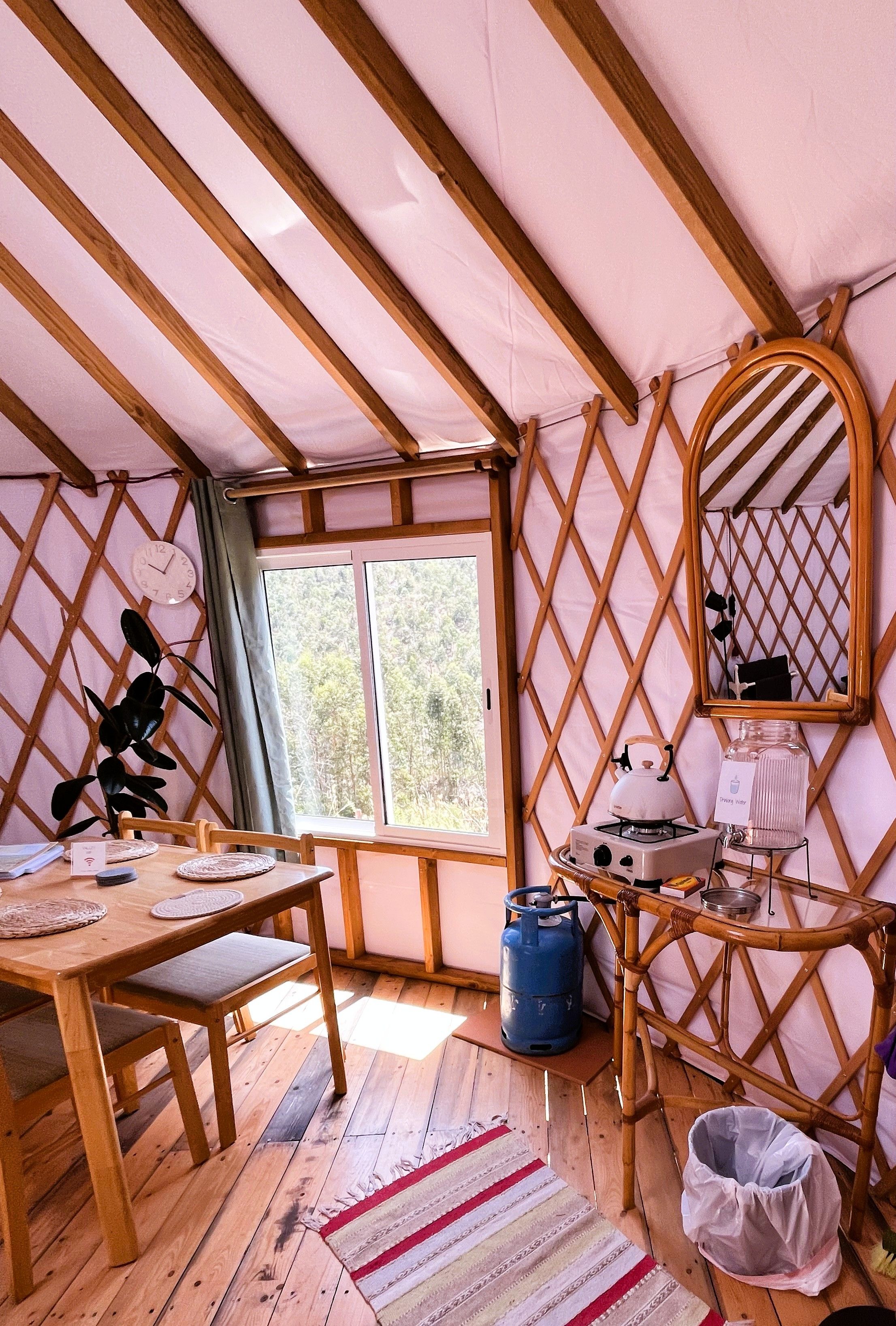Een gezellige kamer met een houten tafel, een stoel, een raam, een spiegel en een fornuis.